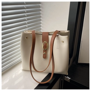 Detail of minimalist cream tote bag with brown leather straps and gold oval hardware