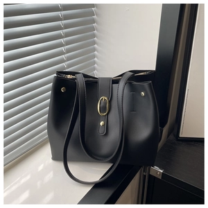 Detail of soft black leather bucket bag with gold oval buckle and zipper closure