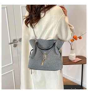 Detailed view of silver glitter crossbody bag with black handles and golden S pendant