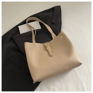 Detail of beige faux leather tote with golden oval metal buckle and fine stitching