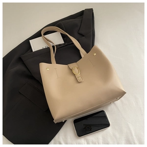 Detailed top view of beige bucket bag with golden buckle and metal base studs