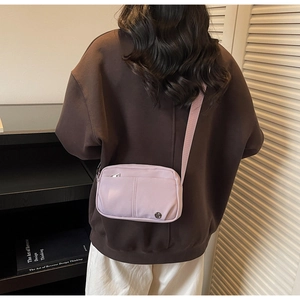 Detailed back view of a lavender nylon crossbody bag with front zipper and metal logo
