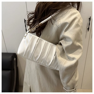 Detail of white pleated shoulder bag with soft leather texture and golden metal buckle