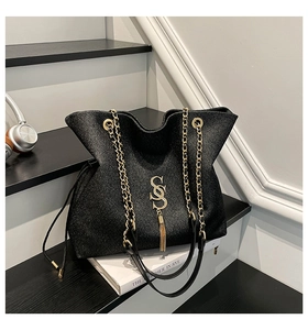 Detail of black glitter tote bag with gold SOS logo, tassel and metal chain strap