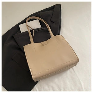 Detailed view of beige soft leather tote bag featuring protective metal feet and fine texture