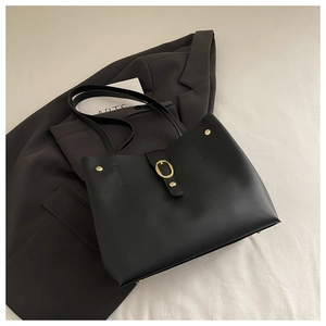 Detail of black leather tote bag featuring gold metal buckle and dual shoulder straps