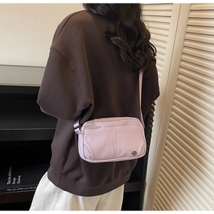 Close-up of lavender crossbody bag with adjustable strap and metal logo on a model