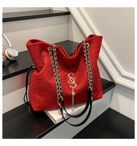Detail of red glitter crossbody bag with gold SS logo and chain strap on stairs