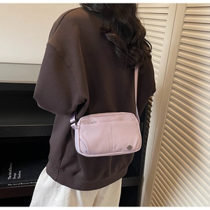 Detail of light purple nylon crossbody bag with silver emblem and front zipper pocket