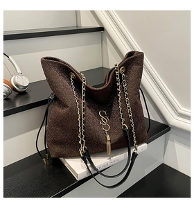Macro detail of brown sequin tote bag featuring gold chain strap and metal S pendant