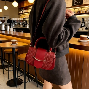 Detail of red woven leather handbag with gold clasp in a stylish cafe setting