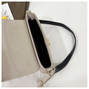 Detail view of beige shoulder bag showing the open interior and gold butterfly clasp