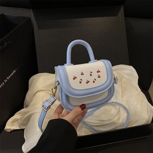 Mini girls cherry print crossbody bag in light blue and white held in a premium gift box
