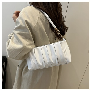 Detail of white pleated cloud bag with woven shoulder strap and golden metal buckle