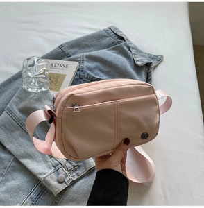 Detail of pink nylon crossbody bag with water-resistant fabric and zip pocket