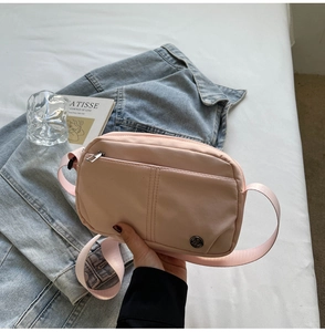 Detailed view of pink casual crossbody bag with metal logo on denim background