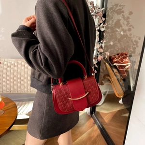 Deep red woven leather handbag with crescent gold buckle shown on model shoulder