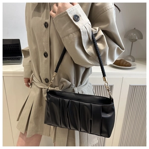 Detail of black pleated cloud bag with woven strap shown on a modern lifestyle background