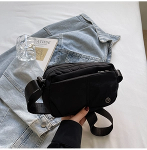 Close-up of black nylon crossbody bag featuring multi-pocket zippers and metal logo