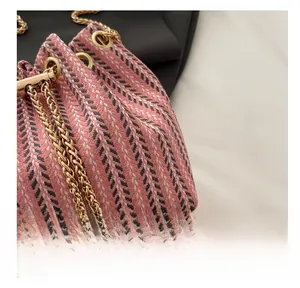 Detail of tweed bucket bag with woven stripes, gold chain, and pearl pendant accent