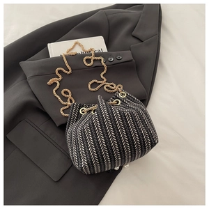 Detail of woven bucket bag featuring chic pearl base and elegant gold chain strap