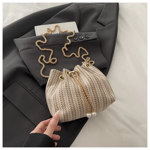 Detail of woven bucket bag featuring herringbone pattern and elegant pearl drawstring charms