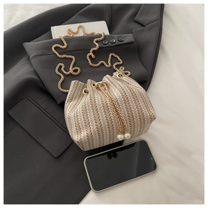 Detail of woven bucket bag featuring herringbone pattern and elegant pearl drawstring