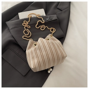 Detail of woven bucket bag featuring V-shaped texture, chain strap and pearl charms