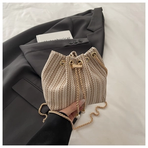 Detail of beige chevron woven bucket bag with pearl drawstring and gold chain strap