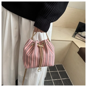 Close-up of pink woven bucket bag with gold chain strap and pearl charms detail
