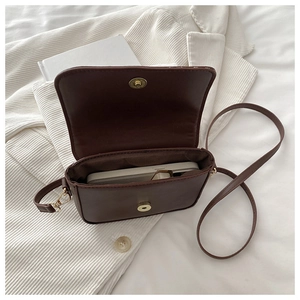Detail view of the deep brown leather saddle bag interior holding a smartphone