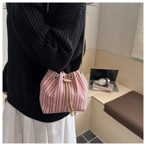 Detail of pink and black tweed bucket bag with gold chain and pearl drawstring charms