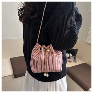 Detailed view of pink woven bucket bag with pearl drawstring and metal chain strap