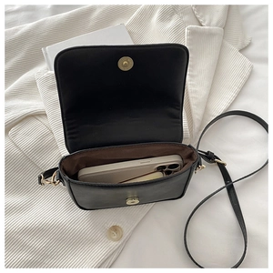 Detail view of black saddle bag interior with phone and cosmetics showing storage capacity