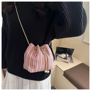Detail of pink and black woven bucket bag with pearl drawstring and gold chain strap