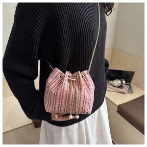 Detail of woven bucket bag with pink navy stripes, gold chain, and pearl drawstring