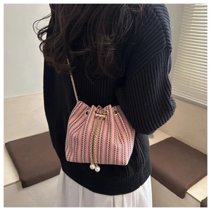 Detail of pink and black tweed bucket bag with gold chain and pearl drawstring charms