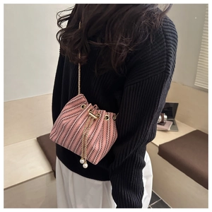 Detail of pink and black striped tweed bucket bag with pearl drawstring and gold chain