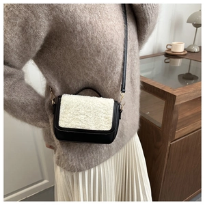 Detail of a vintage saddle bag in black leather and white faux fur on a cozy model