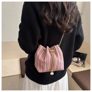 Detail of pink and black woven bucket bag with pearl drawstring and gold chain strap