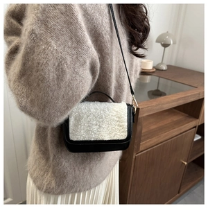 Detail of plush contrast saddle bag worn by model in a cozy interior setting