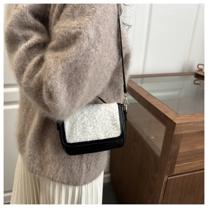 Detail of a vintage saddle bag with black leather and white fuzzy fleece on a model