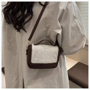 Mini wool saddle bag with brown leather trim and wide strap shown on a beige trench coat