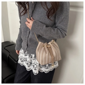 Detail of beige woven bucket bag with pearl drawstring and golden chain strap