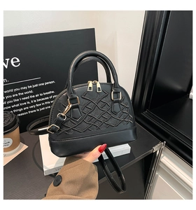 Detail of elegant black shell bag with intricate embroidery and gold hardware