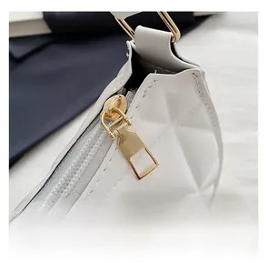 Macro detail of gold metal zipper and white quilted rhombus pattern on a shoulder bag