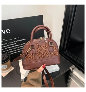 Detail of dark brown shell-shaped crossbody bag featuring ornate embroidery and double zipper