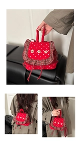 Detail of red polka dot mini backpack featuring gray plaid trim and 3D flower accents