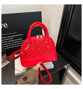 Close-up of red shell-shaped handbag featuring intricate embroidery and gold hardware