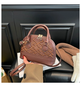 Detailed macro view of the brown leather shell bag featuring crown embroidery and golden hardware